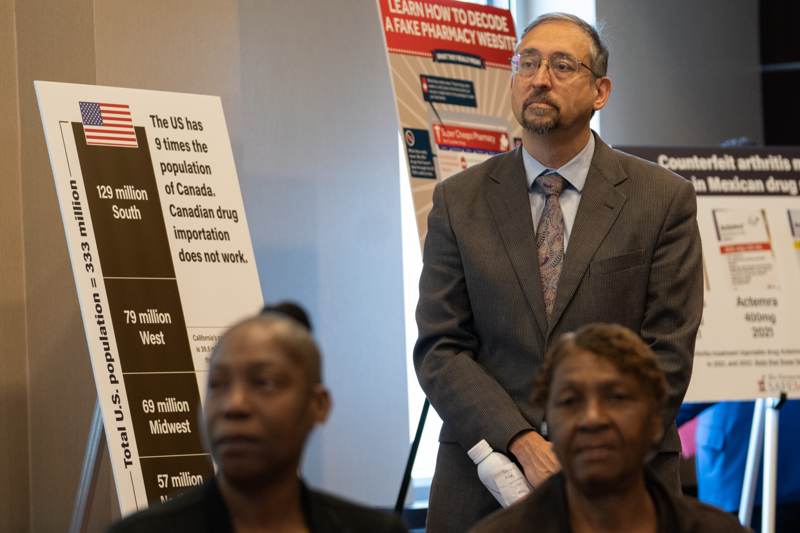 People listening at the briefing with posters on stands behind them.