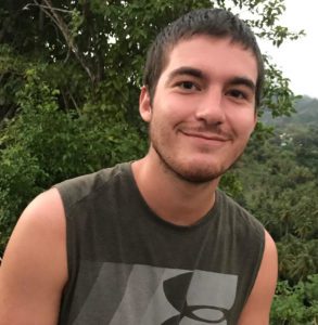 Young man in a black shirt in a green outdoor setting