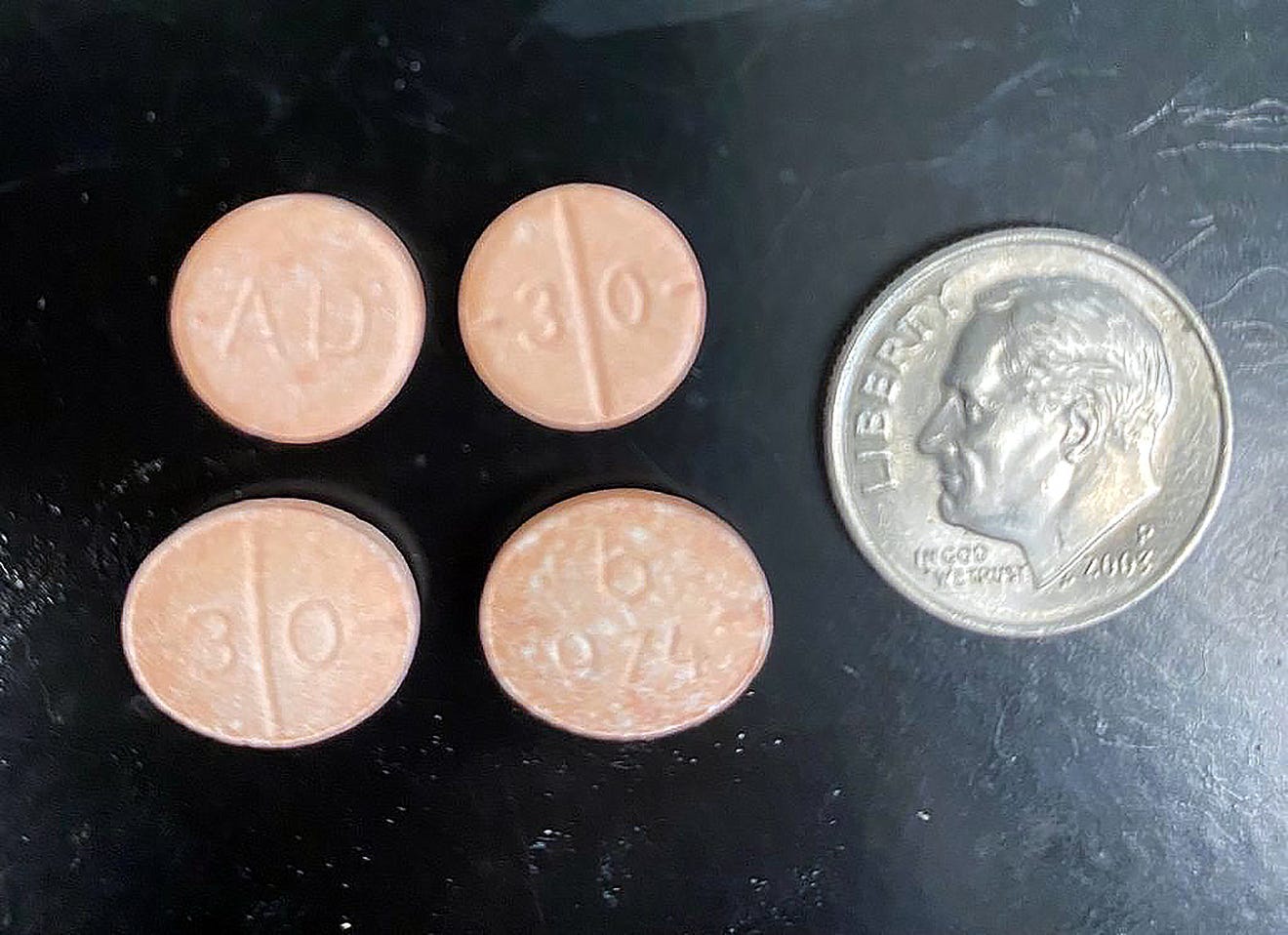 orange pills with a dime for size reference