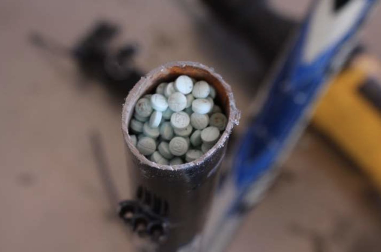 Sawed off bike frame with blue pills in it