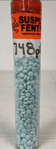 Blue pills in a cylinder with a red label at the top