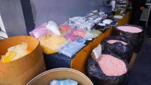 Brightly colored pills in garbage bags and cardboard drums
