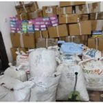 white bags and cardboard boxes piled haphazardly in a storage room