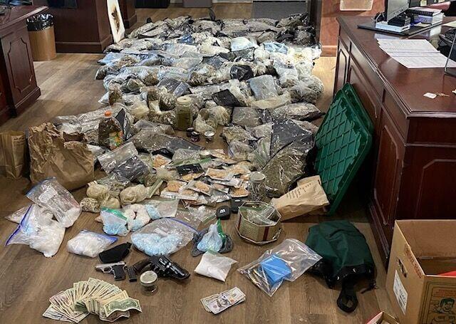 A messy pile of cash and drugs on the hardwood floors.