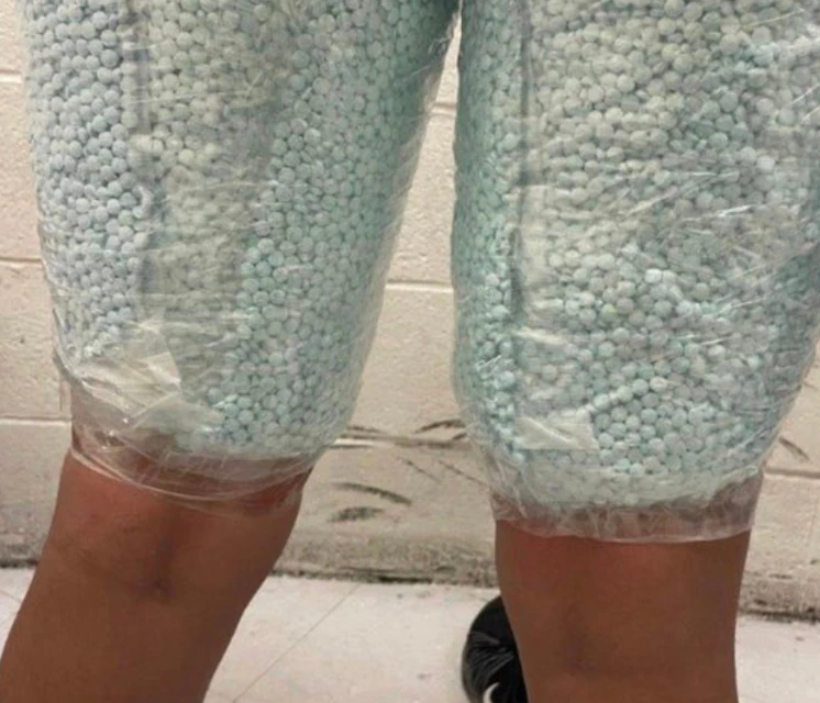 close up of blue fentanyl pills taped around a person's legs
