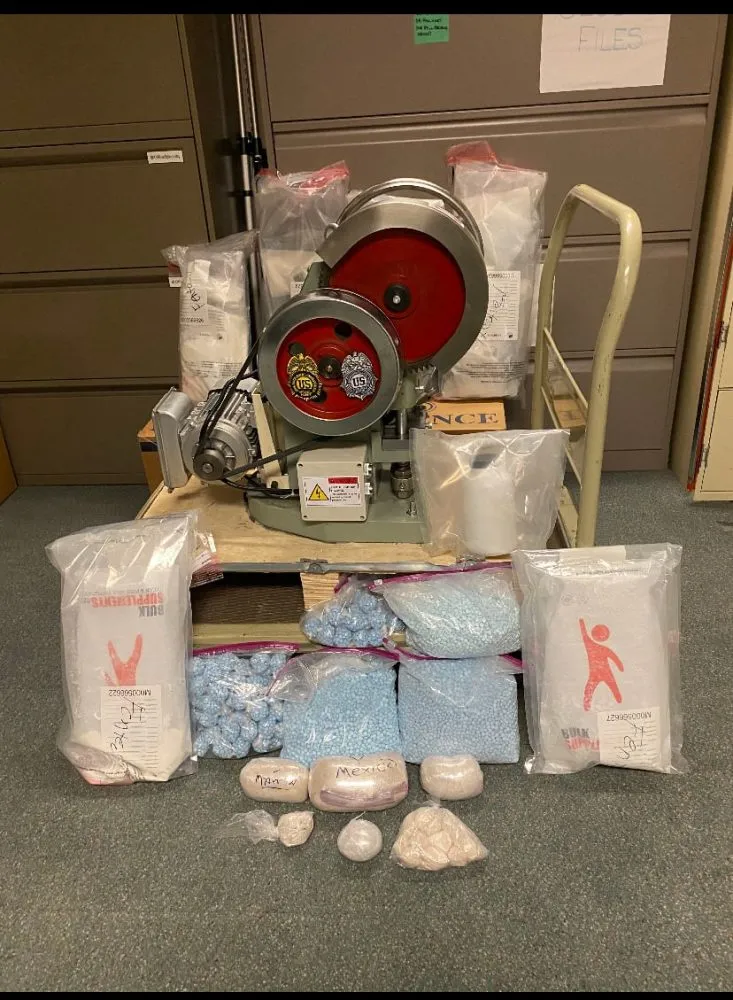 drug seizure photo with pill press and bags of pills