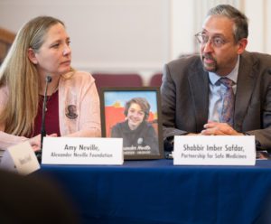 A woman and a man sitting at a table with a picture of a teenager between them