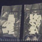 two baggies of white pills on a blue surface