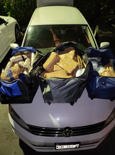 VIew a white car from the front with packages piled on top of the hood