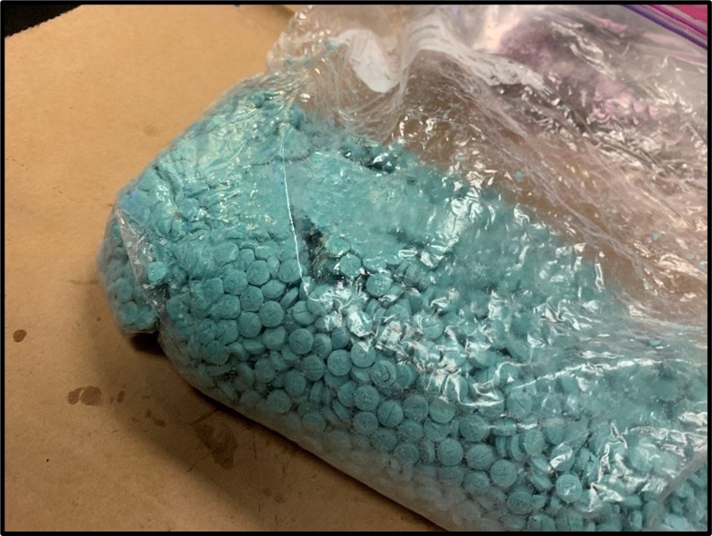 Bright turquoise pills closely packed in a clear plastic bag