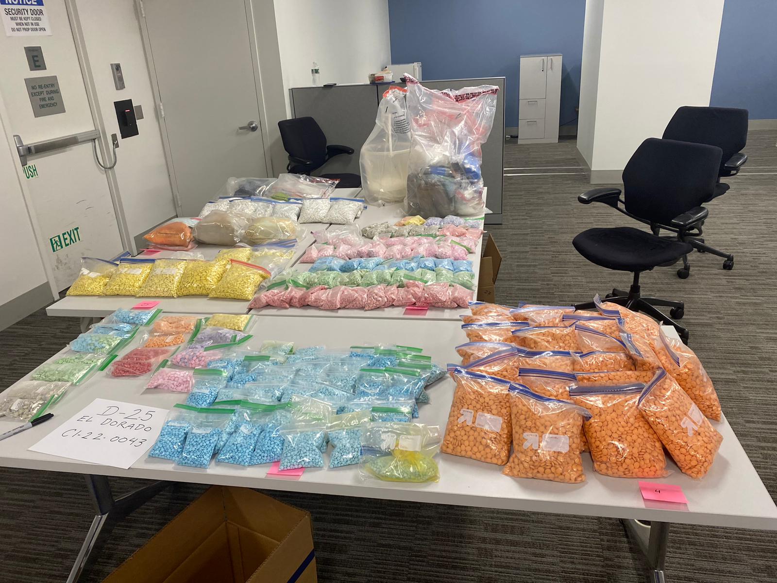 Several tables of bagged pills laid out on white tables