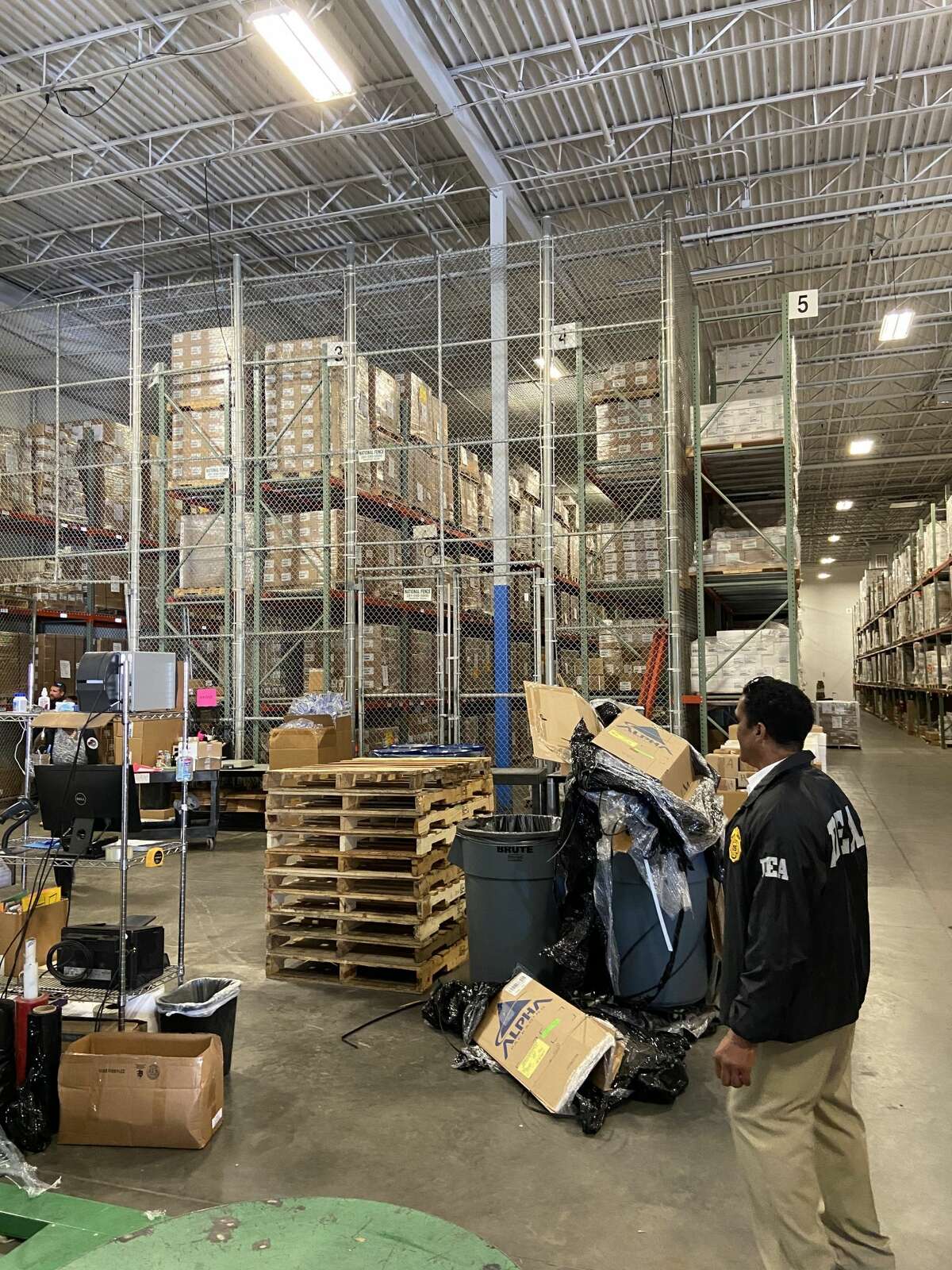 A man stands in a giant warehouse, his back to the camera