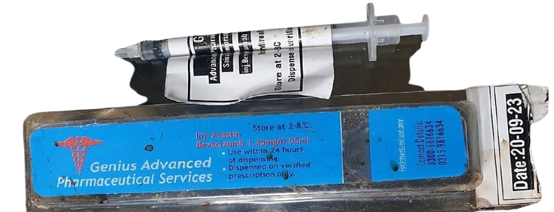 A drug package with a blue label inscribed "Genius Advanced Pharmaceutical Services" and a syringe attached.