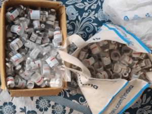 a cardboard box and tote bag full of glass vials