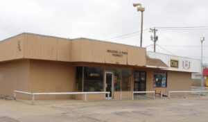 a brown pharmacy building on a concrete lot on an overcast day